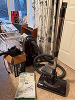 Full view of Kenmore canister vacuum with hose, wand, power head, vacuum bags in packaging, user manual, and Black & Decker Dirtbuster in box