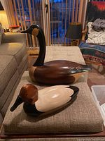 Both carved wood birds (goose and duck) displayed on ottoman