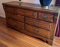 Front view of double size wood dresser showing all seven drawers, wood grain finish and metal drawer pulls.