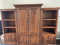 Photo showing the central TV console flanked by matching bookshelves, all wood with medium brown finish and cabinets.