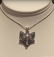 Close-up front view of silver Viking wolf head pendant on necklace.