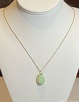 Full view of 21-inch silver necklace with jade pendant displayed on mannequin bust.