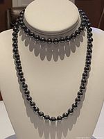 Front view of a single strand hematite beaded necklace displayed on a white bust form.