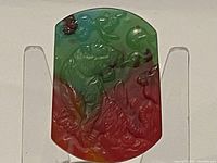 Front side of the rectangular carved jade pendant showing detailed tiger and landscape carving.