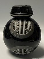 Front side view of black spherical Star Wars BB-9E robot showing gray vent-like details and glossy black finish