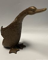 Side view of the vintage cast metal duck planter showing the textured finish and elongated neck and bill.