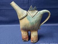 Side view of the vintage handcrafted Raku ceramic teapot showing spout, handle, and textured surface with earthy color tones.