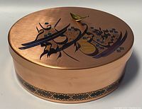 Top and side view of vintage Persian round copper covered box with decorative calligraphy and inlaid artwork on the lid and side band.