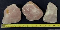 Three rose quartz pieces shown together with measuring tape to demonstrate size.