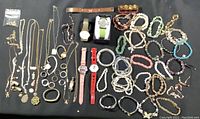 Full view of various jewelry pieces laid out including watches, rings, bracelets, and necklaces.