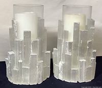 Pair of glass candleholders featuring sculpted abstract ice-like clear glass outer shells with white pillar candles inside.