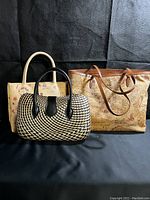 Three handbags: left beige straw floral patterned bag, center black and tan woven bag, right large brown leather tote with vintage world map print.