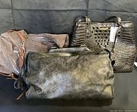 Three handbags arranged side by side on dark background