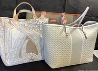 Two tote bags: a white and gray patterned Sondra Roberts tote and an Etoffe canvas tote with beige handles and orange interior visible behind it.