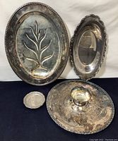 Full set of four silverplate serving pieces arranged: round platter with small bowl in center, oval footed meat platter, oblong server, and coaster-sized plate.