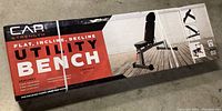 Boxed CAP Strength utility exercise bench seen from front with branding and usage images on side of box.
