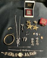 Top view photo showing wide variety of vintage costume jewelry including rhinestone necklaces, earrings, bracelets, rings, and a watch bracelet along with a boxed silver Byzantine icon.