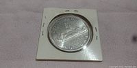 Close-up of reverse side of the 1965 Canada silver dollar coin inside a protective cardboard holder.