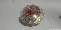 Clear image of the vintage Majak mantel clock with bright red dial and gold numerals housed in a faceted crystal casing.