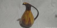 Side view of Blue Mountain Canada Pottery ceramic pitcher showing body shape, handle, and spout with brown and yellow glaze.