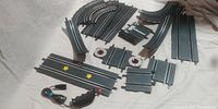 Multiple angled photos showing the layout and variety of Carrera slot car track pieces along with one wired remote control.