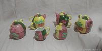 Photo of entire Country Inn Collection tea set with four teapot cups, creamer, and sugar bowl displayed in a line