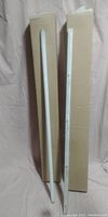 Two fluorescent light tubes side by side standing vertically against a cardboard box.