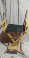 Front and left side view of wooden folding director's chair with black fabric seat and missing back cloth.