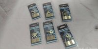 All six Master locks in original plastic blister packaging laid out in two rows of three, showing front view of locks including keys.
