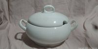 White ceramic soup tureen with lid, side handles and ladle notch photographed closed.