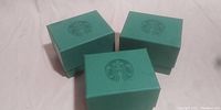 Three green Starbucks-branded boxes shown closed with logo on top.