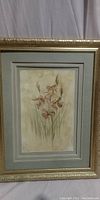 Full view of floral wall art in gold frame with grayish-blue mat