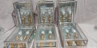 Six Troy CSL wall light fixtures arranged upright showing their glass and metal frames and dual bulb holders.