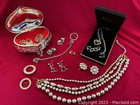 All items displayed on red fabric showing trinket box and assorted jewelry