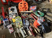 Wide view of all tools laid out on floor, showing many hand and power tools, extension cords, gloves, knee pads, and drill kit in box