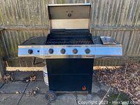 Full front view of hooded Char-Broil gas grill on wheels with five control knobs and propane tank below.