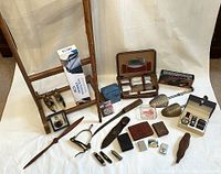 Full view of lot showing travel case, carved nutcracker, cutting tools, vintage ash tray, wallets, lighters, shoe stretchers, belts, walking stick, and wooden valet stand.