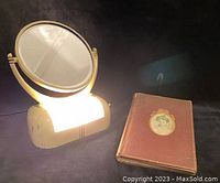 Photo of the vintage light-up vanity mirror illuminated next to the 1899 Scribner's book