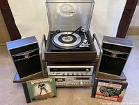Full setup showing turntable on top, cassette deck and receiver stacked on cart with speakers and front-row record sets