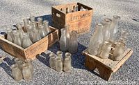 Wide view showing multiple vintage glass bottles scattered and stored in three rustic wooden crates, one labeled 'Berry Springs'