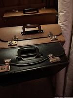 Front view of two leather lawyer briefcases stacked, visible brown and black with combination locks and leather handles
