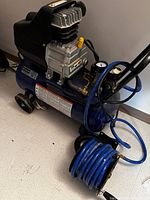 Front and side view of blue portable compressor on wheels with coiled blue hose attached