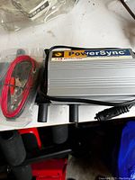 PowerSync power inverter with attached cables and red and black battery clips in packaging.