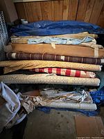 Stack of rolled fabrics showing multiple layers and colors including brown, tan, beige, red, and blue.