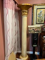 Full view of the tall torchère floor lamp next to a window and speaker, showing its height and proportions with an ivory column and gold leaf capital.