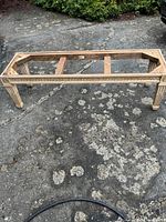 Full view of rectangular solid wood bench seat frame with decorative carved edge and tapered legs.