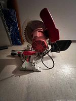 Side view of electric miter saw showing the blade, red blade guard, and handle