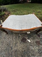Top view of a solid wood ottoman frame with spring base, showing the mesh fabric covering and carved wooden legs.
