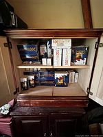 Open cabinet shelves showing multiple boxes of Christmas lights, mainly 100 and 200 count indoor and outdoor strings.