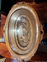 Top view of the oval solid wood side table showing carved horse design under glass top.